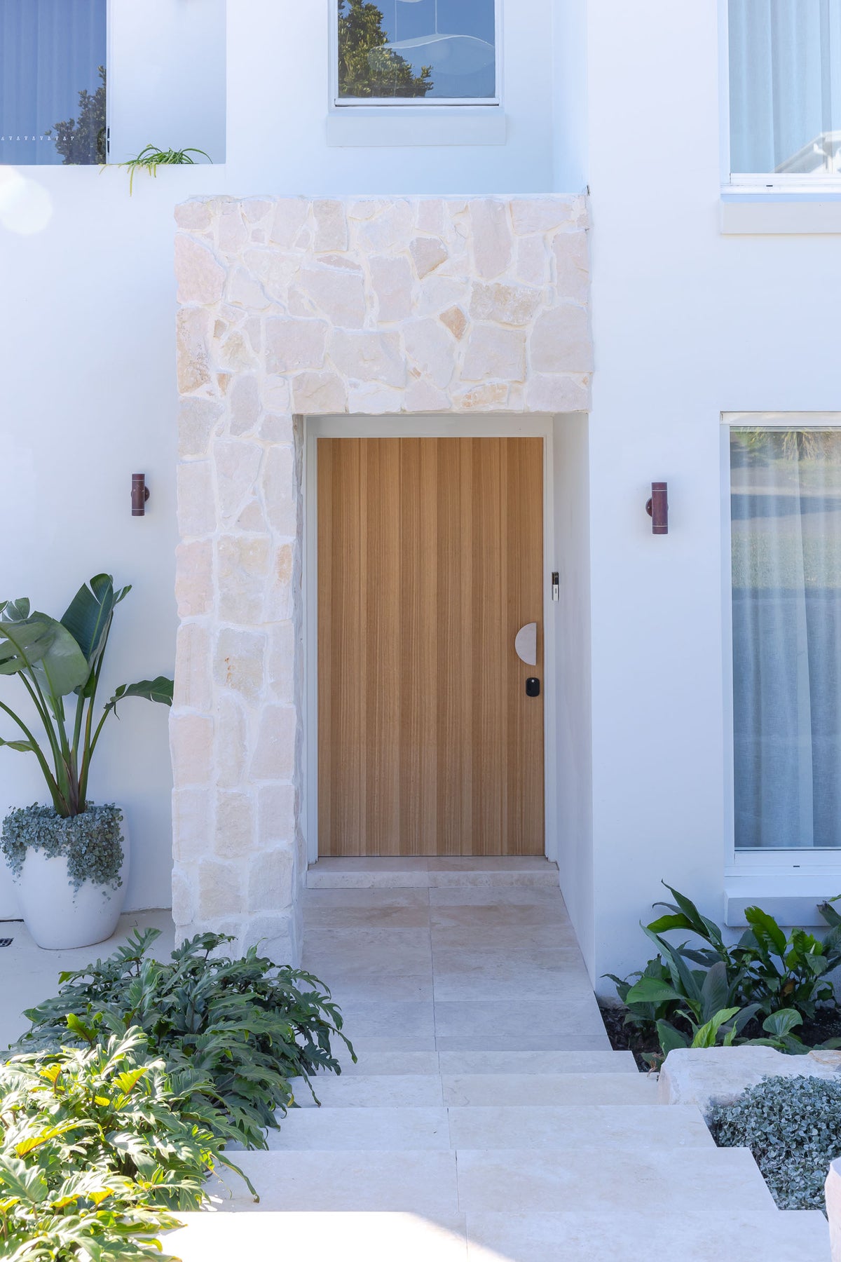 HAAUS.7 timber entry door within stone-clad archway
